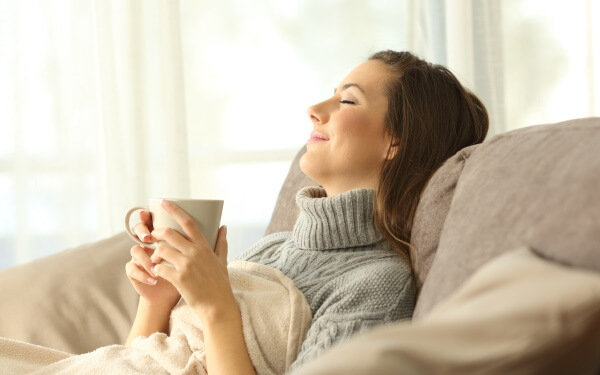 ソファでくつろぎ深呼吸する女性