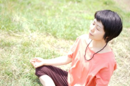 草の上で目を閉じて瞑想する女性